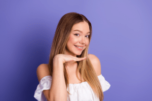 Teen smiling while showing braces against a purple background