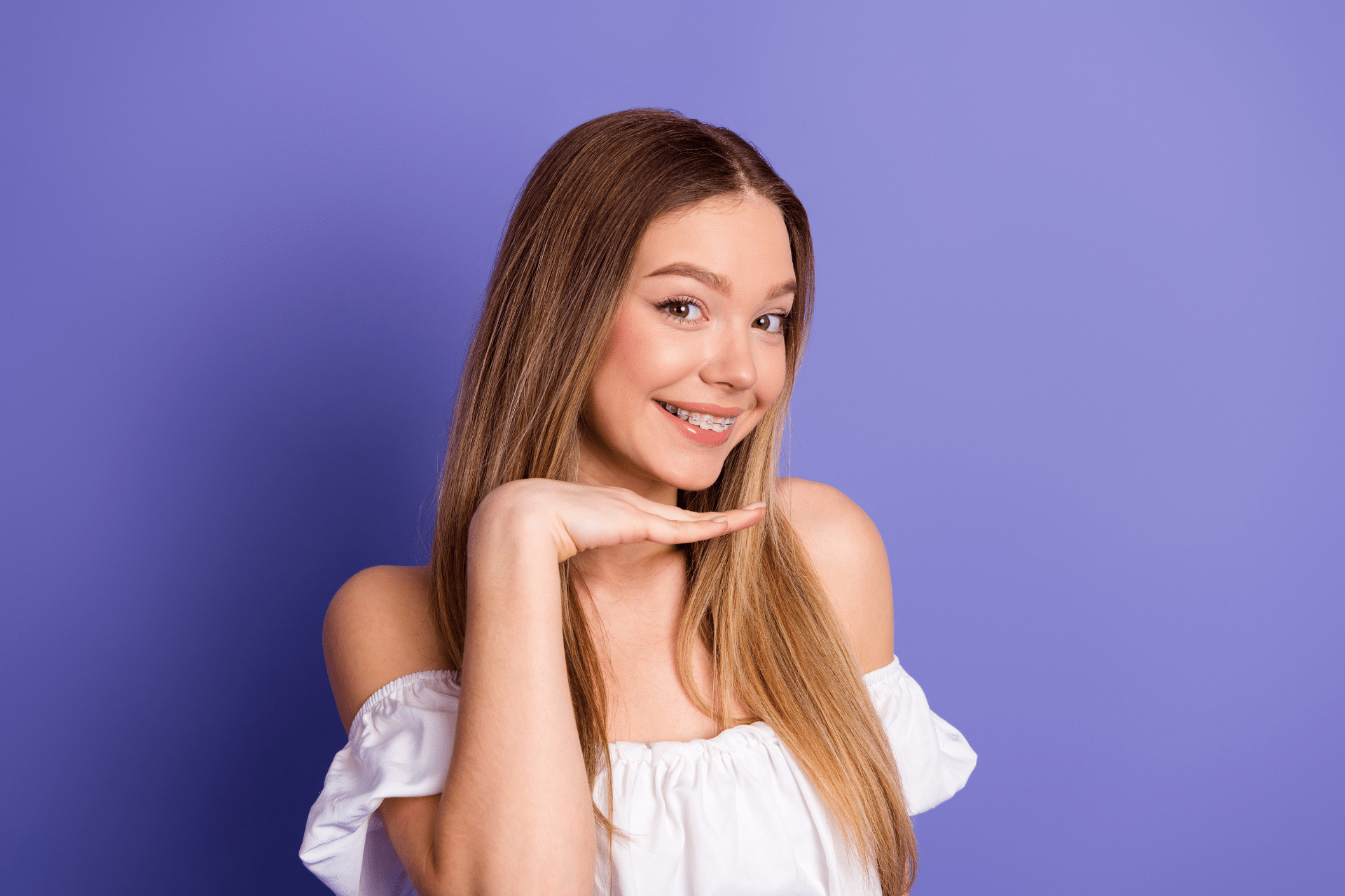 Teen smiling while showing braces against a purple background