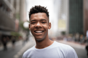 Smiling young man wearing braces outdoors in a city setting